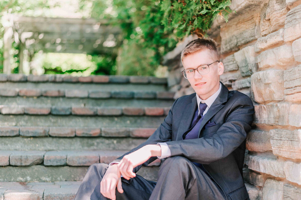 Sitting on some stone steps leaning on the sides with his back. 