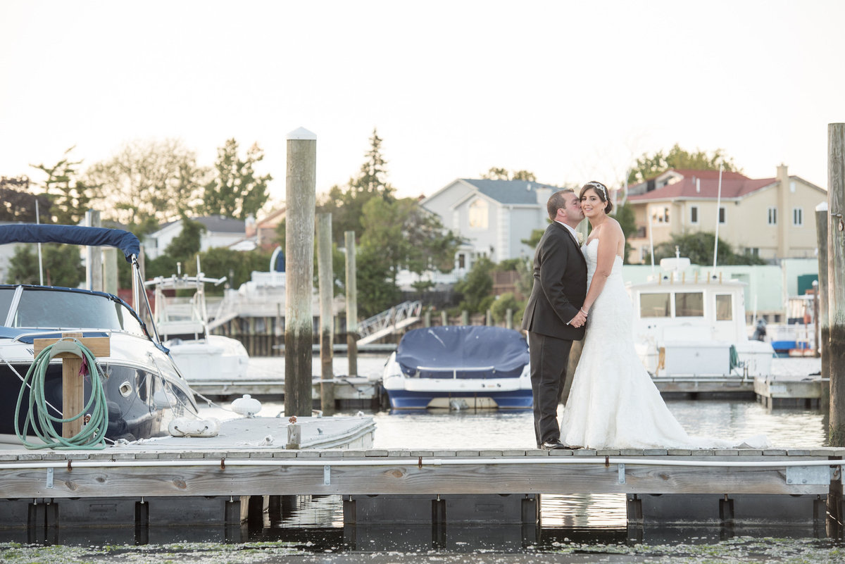 photo of groom kissing his bride on the dock from wedding reception at Lawrence Yacht and Country Club