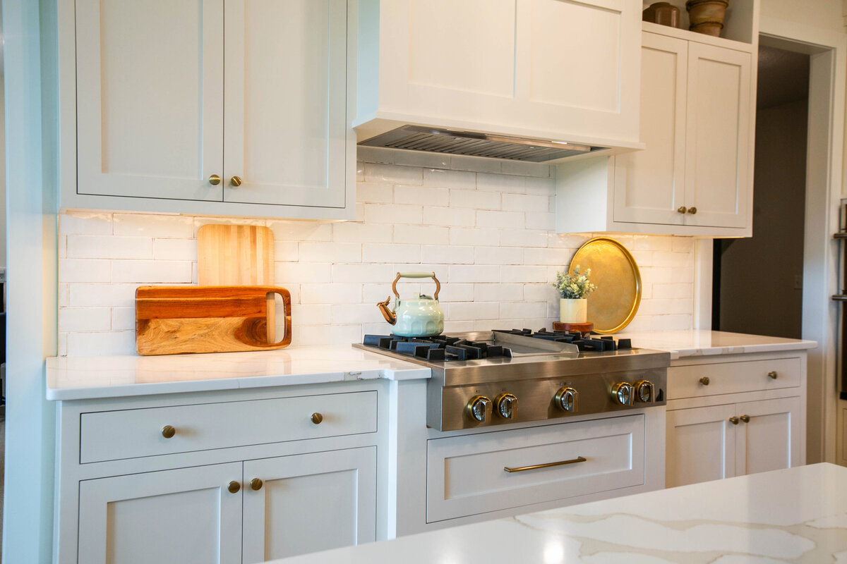 Open kitchen with white cabinets, large island, and quartz countertops in an Otsego custom home