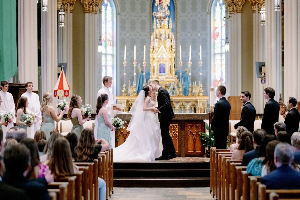 bride and groom kissing during Catholic wedding