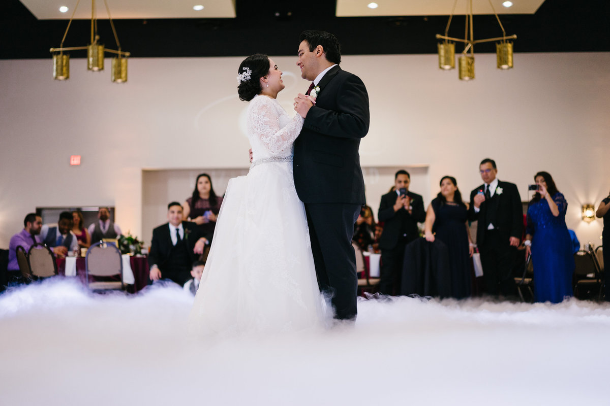 Bride and Groom have first dance in smoke fog at wedding reception at San Fernando Hall in down town San Antonio