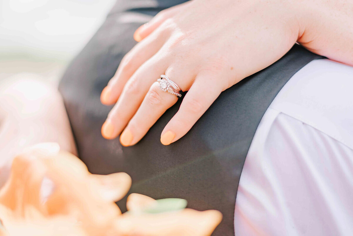 Bride has her hand on the grooms shoulder showing off her rings.