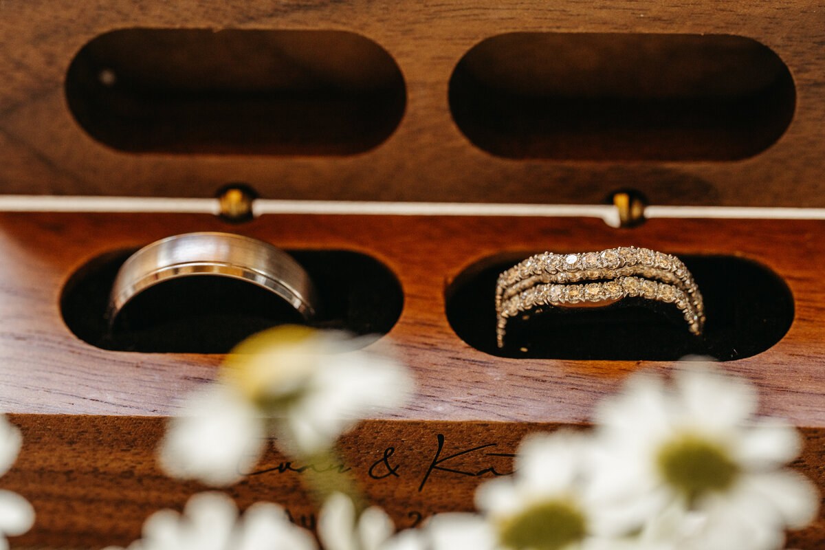 Engagement and wedding rings in wooden box with daisies