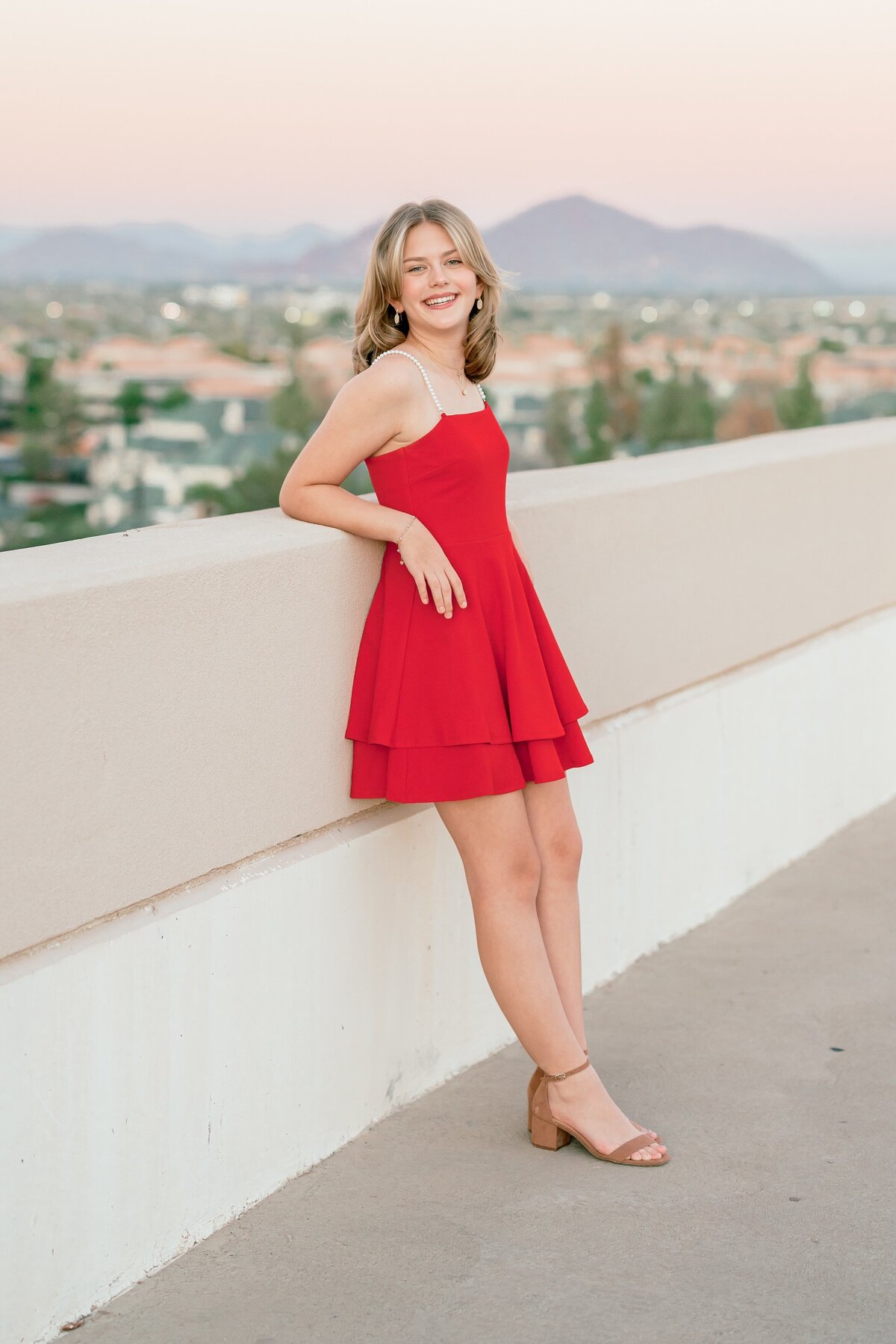 senior girl standing on roof top in downtown phoenix smiling at camera