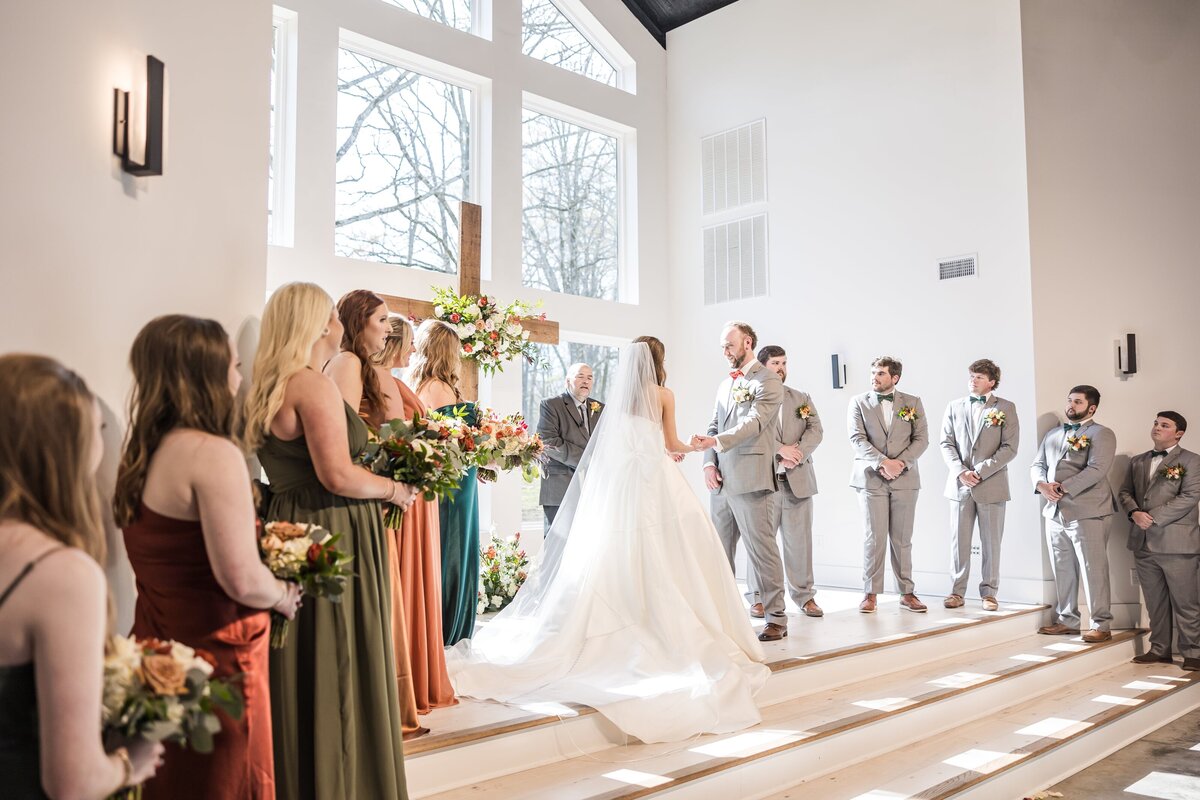 A bride and groom hold hands while standing at the altar during their ceremony