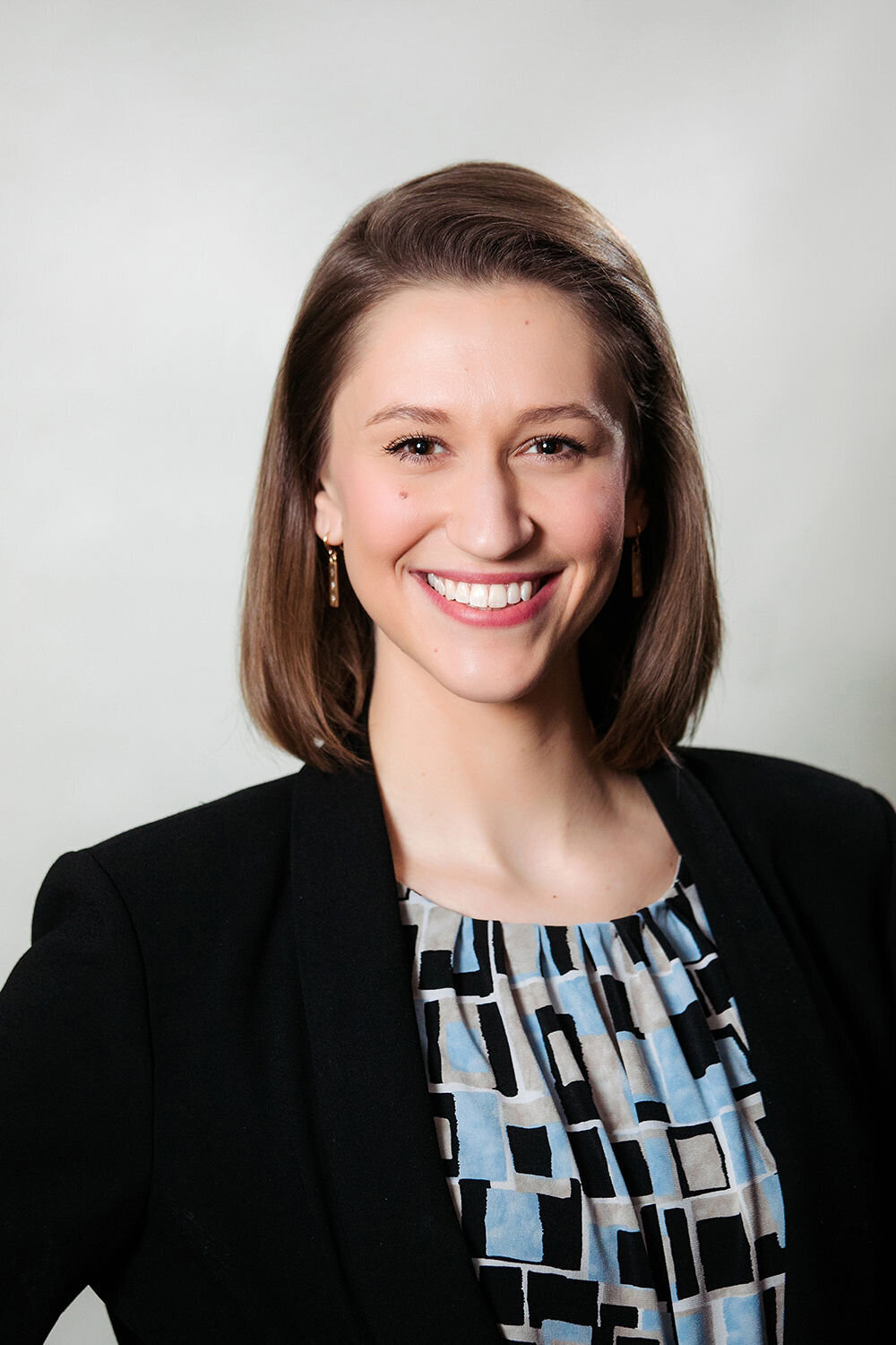 A woman in a patterned shirt smiles.