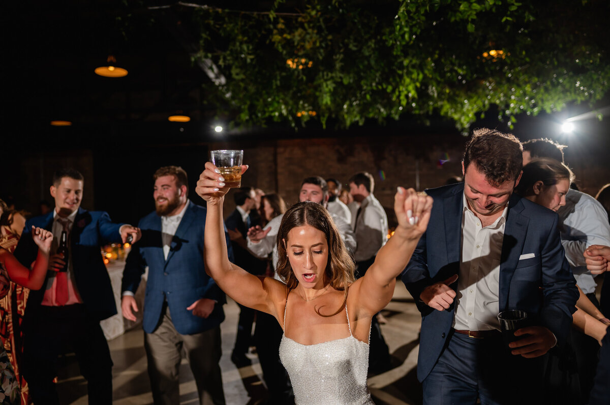 Bride dances with her hands up at her wedding reception at Revel Motor Row in Chicago,Illinois