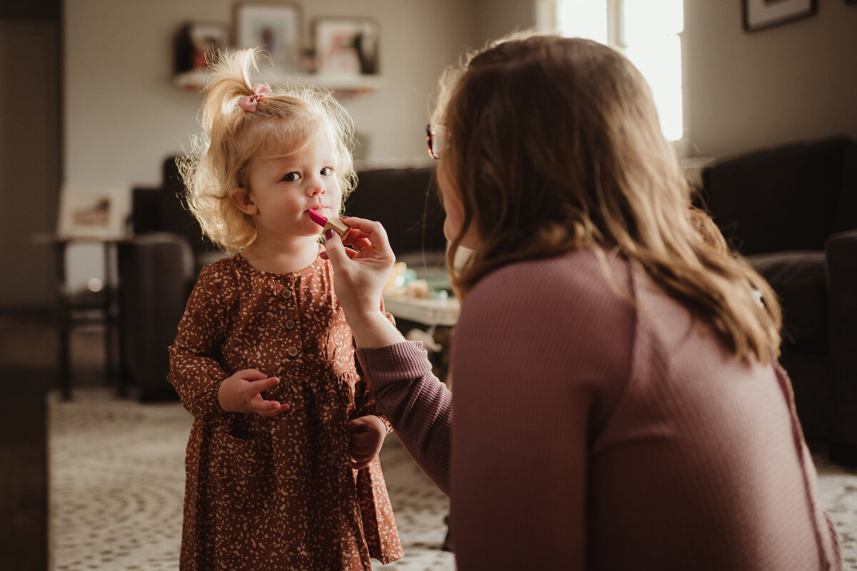 mom putting play lipstick on daughter