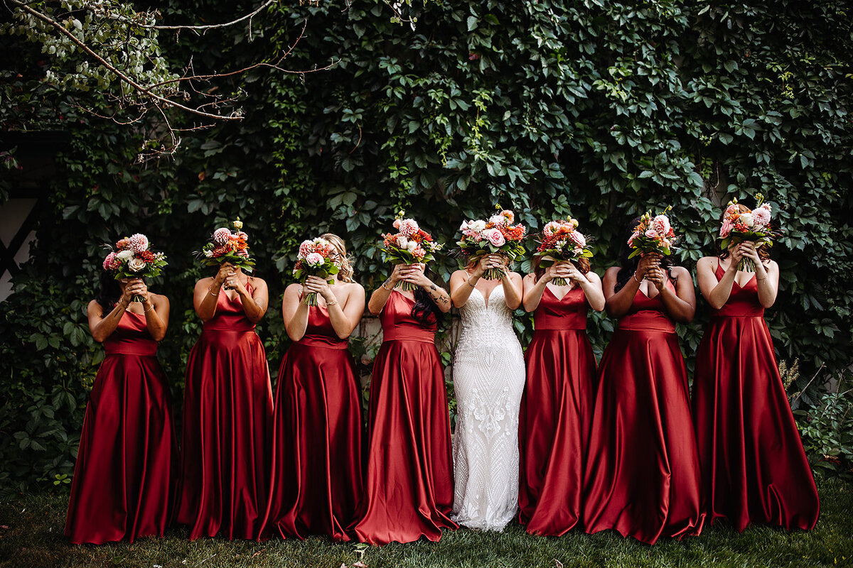 Bride and bridesmaid in rust dresses with pink and rust bouquets.