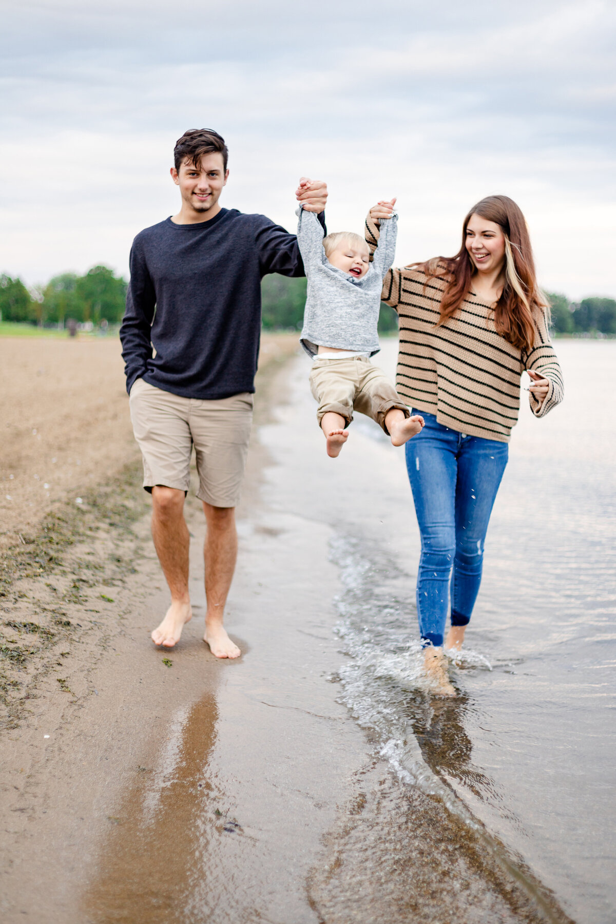 mom-dad-swinging-baby-at-beach
