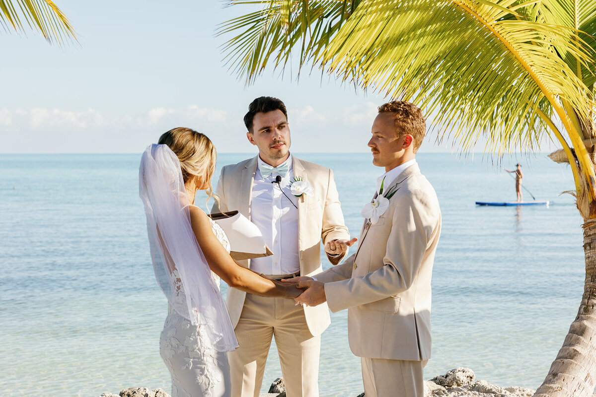Ashley and Hunter stand together, holding hands with the officiant as they exchange vows.