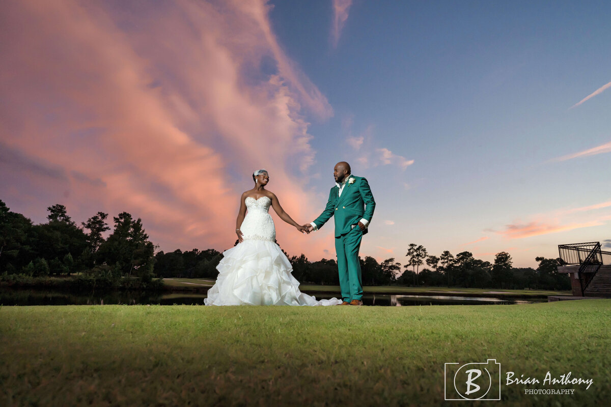 Romantic golden-hour wedding portrait of the couple under a stunning sunset sky.