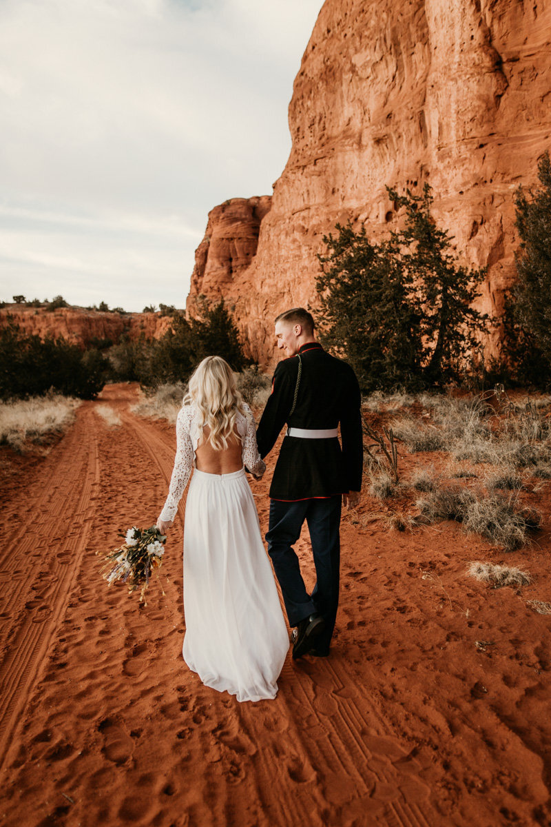 Bride and groom walking along red rocks
