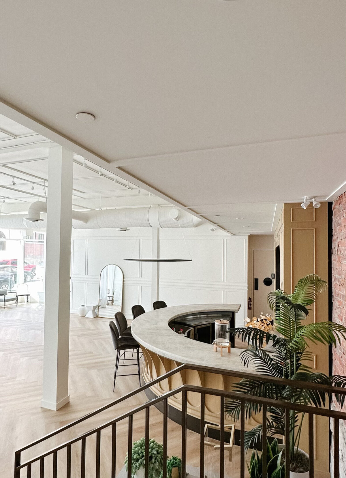 A spacious, modern event venue at Studios at Vic Park in downtown Calgary, featuring large windows with sheer white curtains, herringbone wood flooring, and contemporary furnishings. Bright natural light enhances the elegant and versatile space.