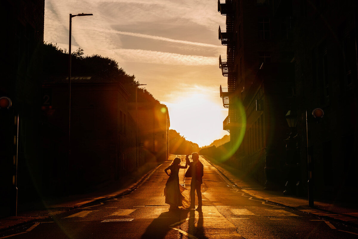 backlit photo of a bride and groom dancing outside The Arches at Sunset