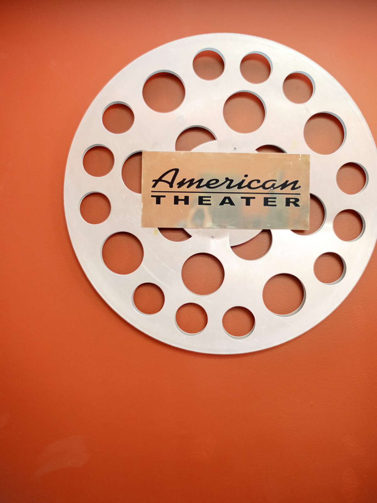 The image shows a film reel labeled 'American Theater', signifying the rich tradition of storytelling through cinema, art, and emotion intertwined with cultural experience.