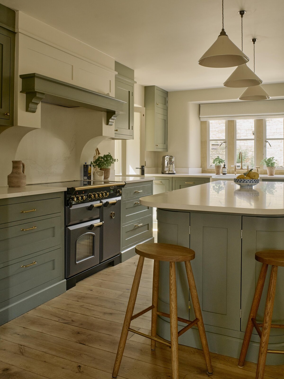 Cotswold green kitchen with bespoke cabinetry and stools