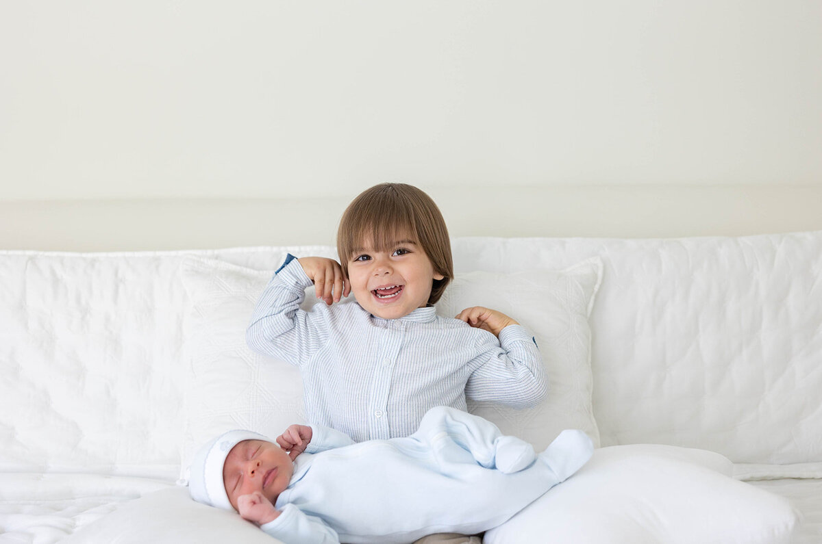  A toddler and newborn sibling share a quiet moment in a softly lit room during a Florida Keys portrait photography session by Claudia Amalia.