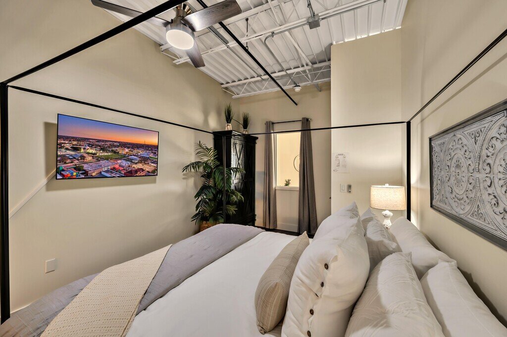 Bedroom with comfortable bedding and smart TV in this 2 bedroom, 2.5 bathroom luxury vacation rental loft condo for 8 guests with incredible downtown views, free parking, free wifi and professional decor in downtown Waco, TX.