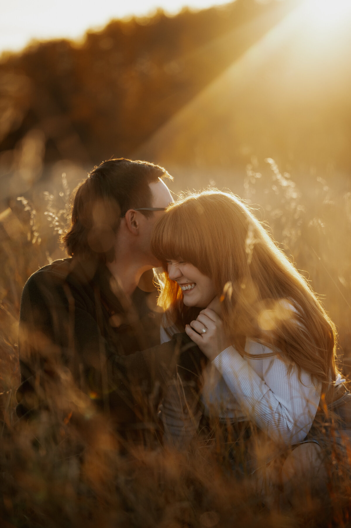 Photograph of Edmonton couple snuggles in field during sunset 