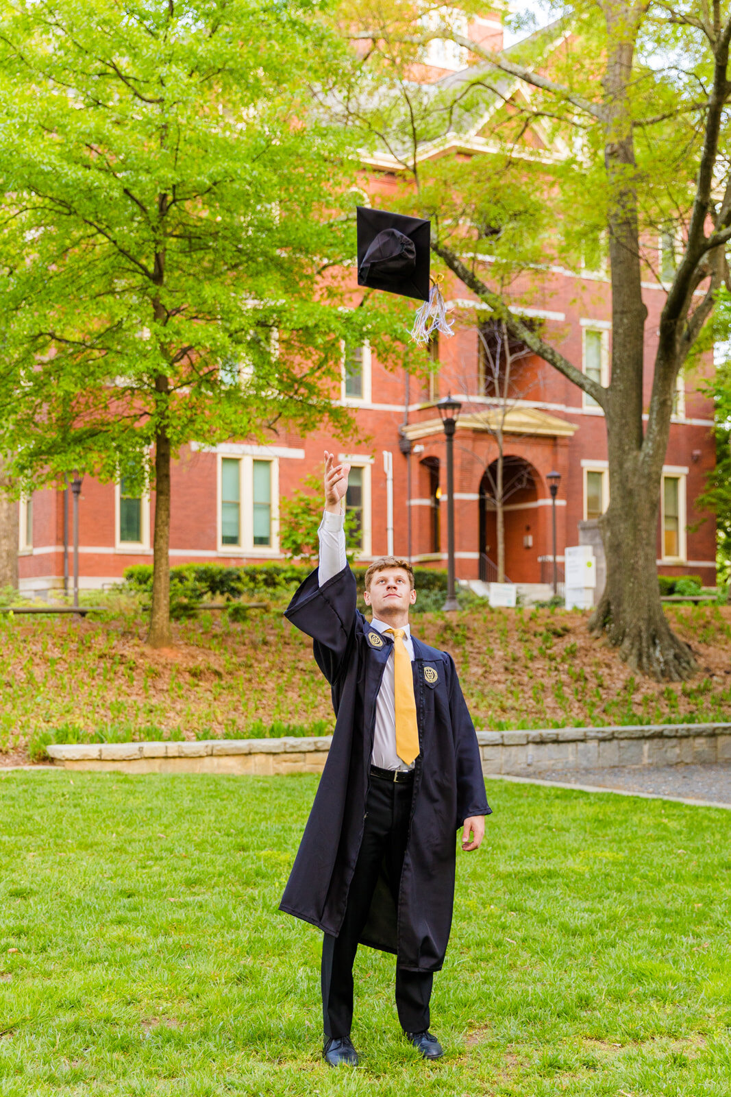 Georgia Tech senior boy throwing his cap in the air during graduation portraits in campus with Atlanta senior photographer Laure Photography