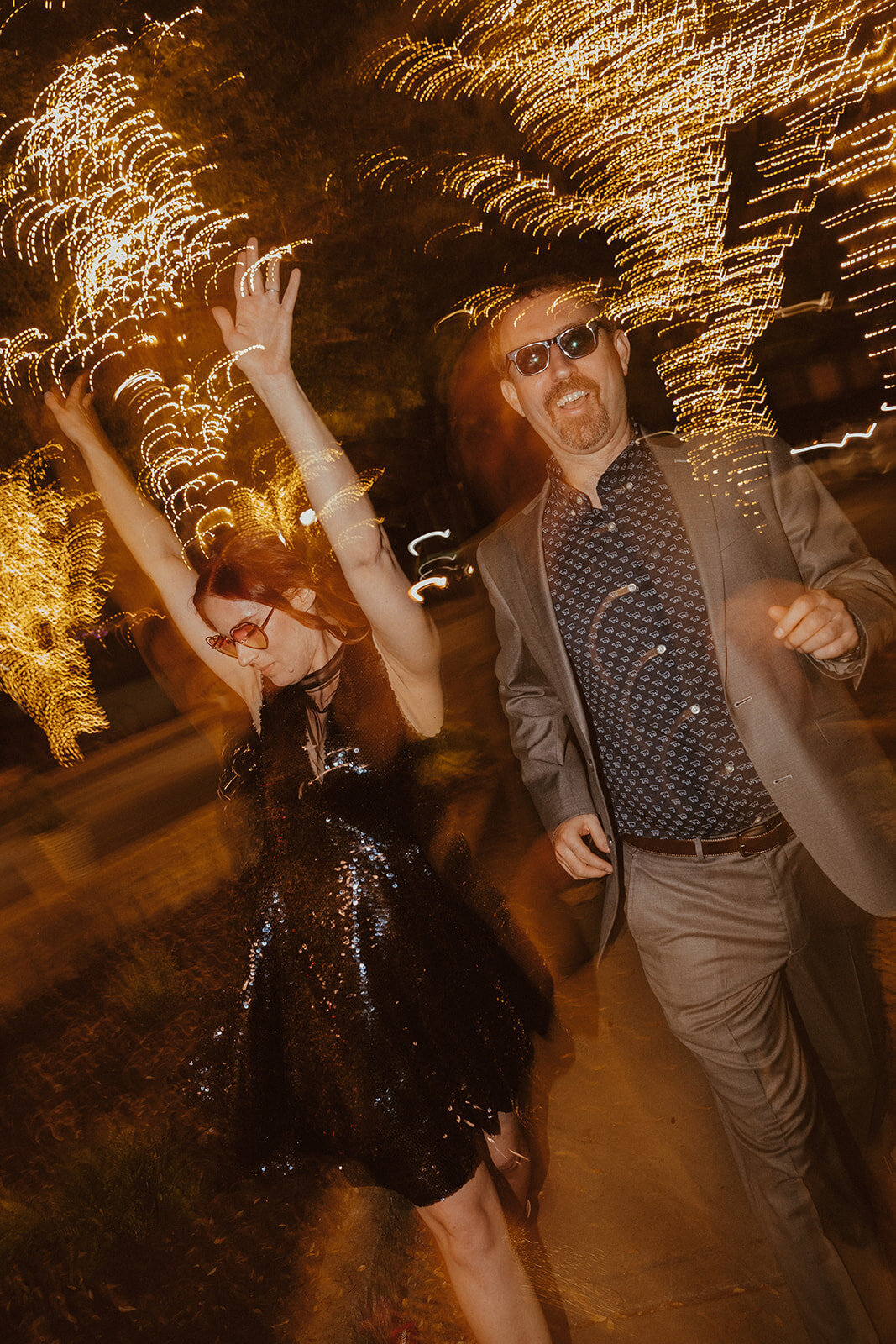 engagement photos skipping down street with twinkle lights