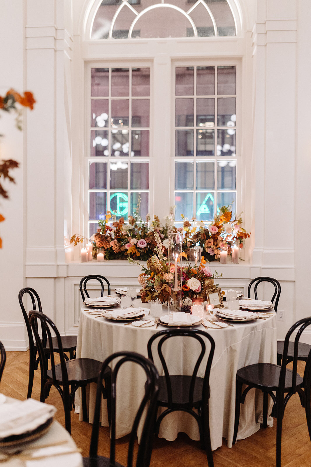 Organic floral centerpieces decorate this autumnal Parisian inspired wedding reception in hues of dusty rose, burgundy, terra cotta, and lavender composed of roses, ranunculus, delphinium, lisianthus, copper beech, and fall foliage. Design by Rosemary and Finch in Nashville, TN.
