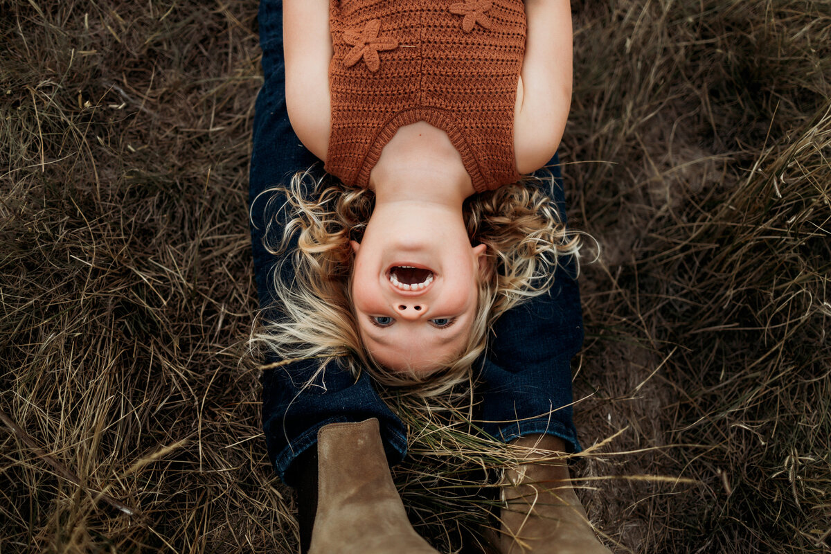 Overhead view of a young daughter laying on her dad legs while laughing