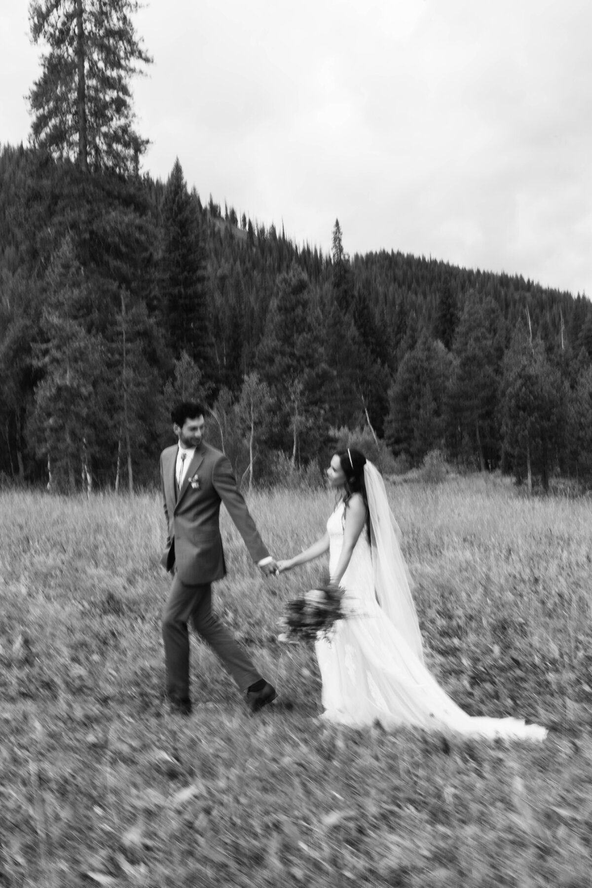 bride and groom walking along at Idaho wedding in nature