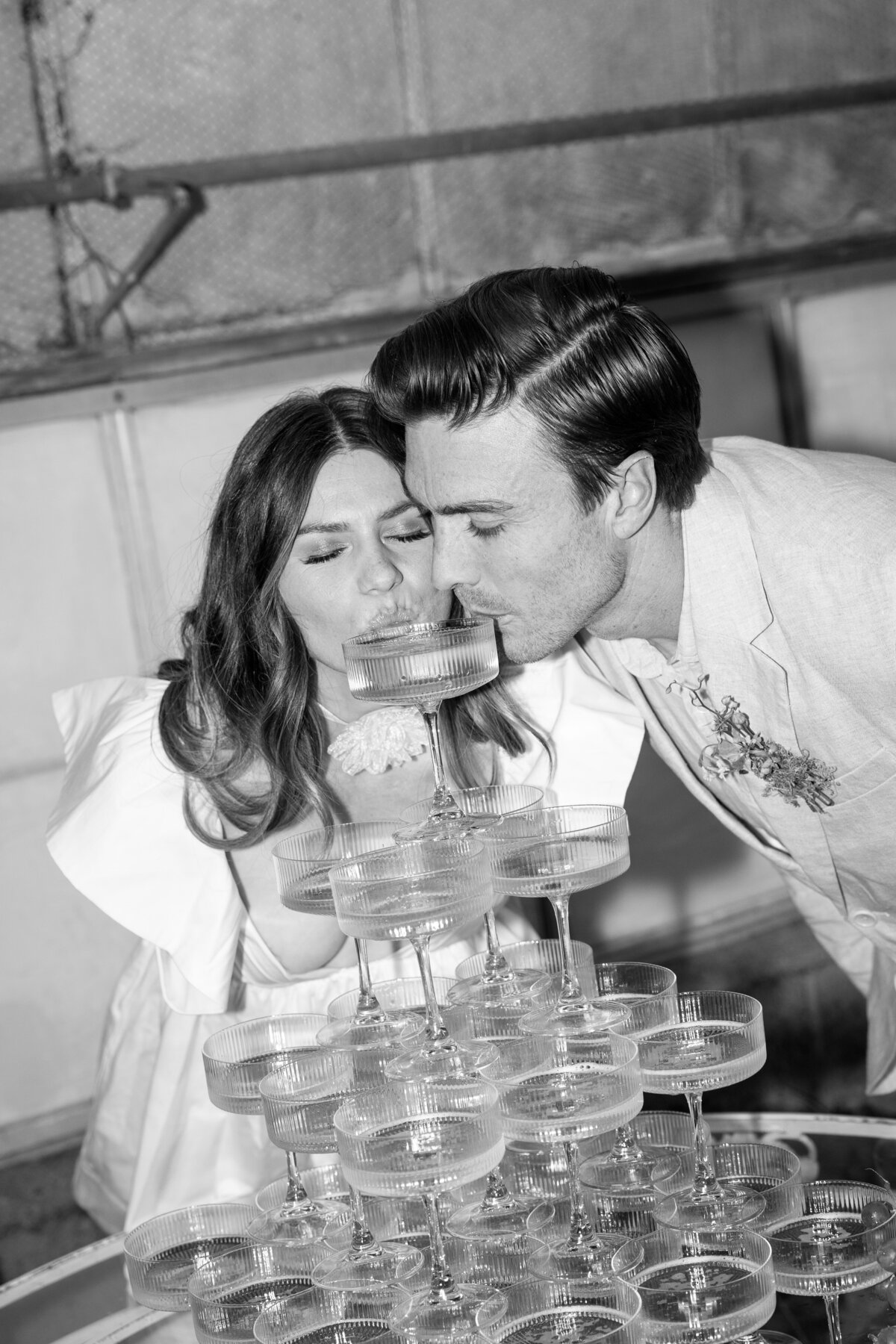 Flash portraits of the couple sipping from their champagne tower, captured by a La Jolla wedding photographer.