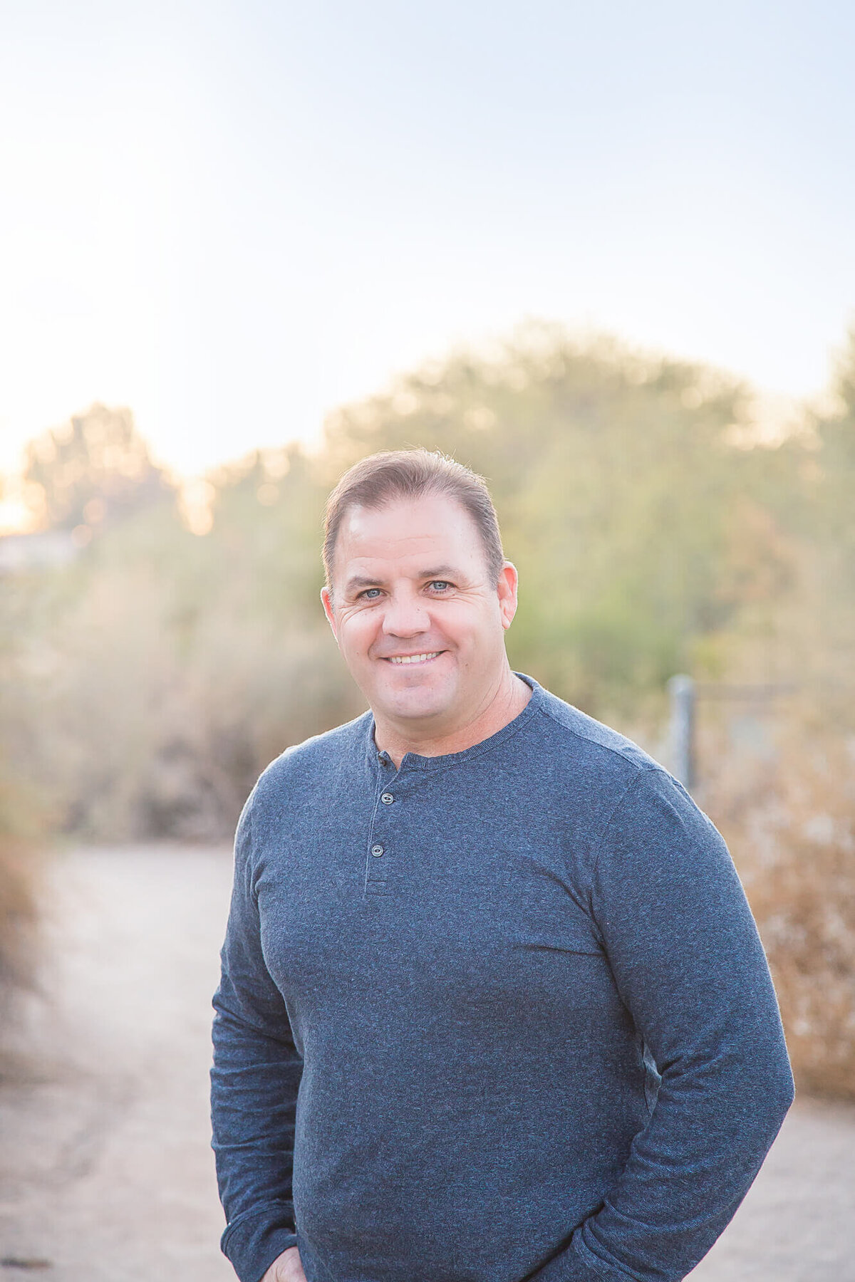 Handsome plumber with brown hair in blue shirt standing on a desert path in Gilbert, AZ