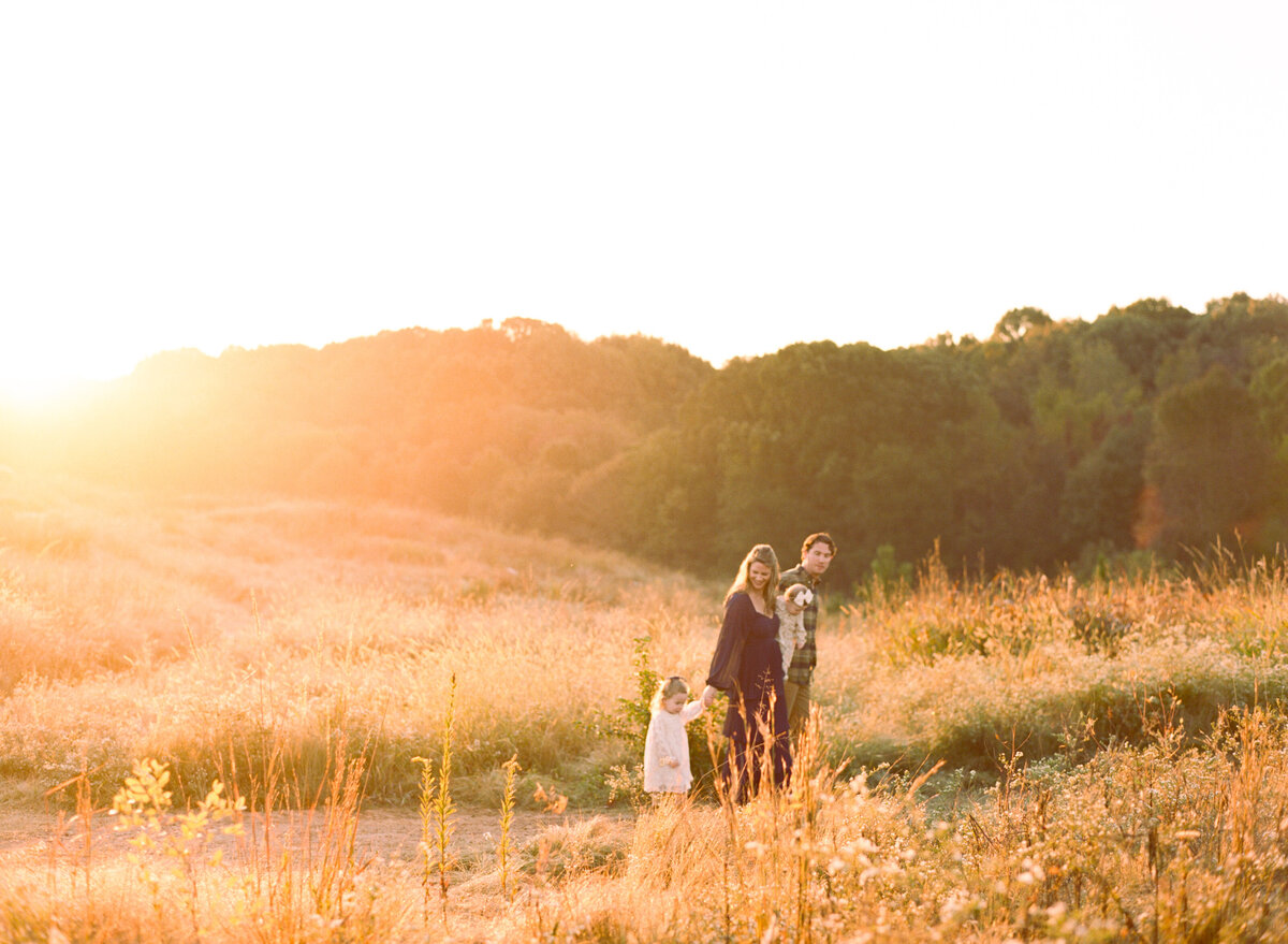Family walks through a field at sunrise at the NC Museum of Art. Image by Raleigh maternity photographer A.J. Dunlap Photography.
