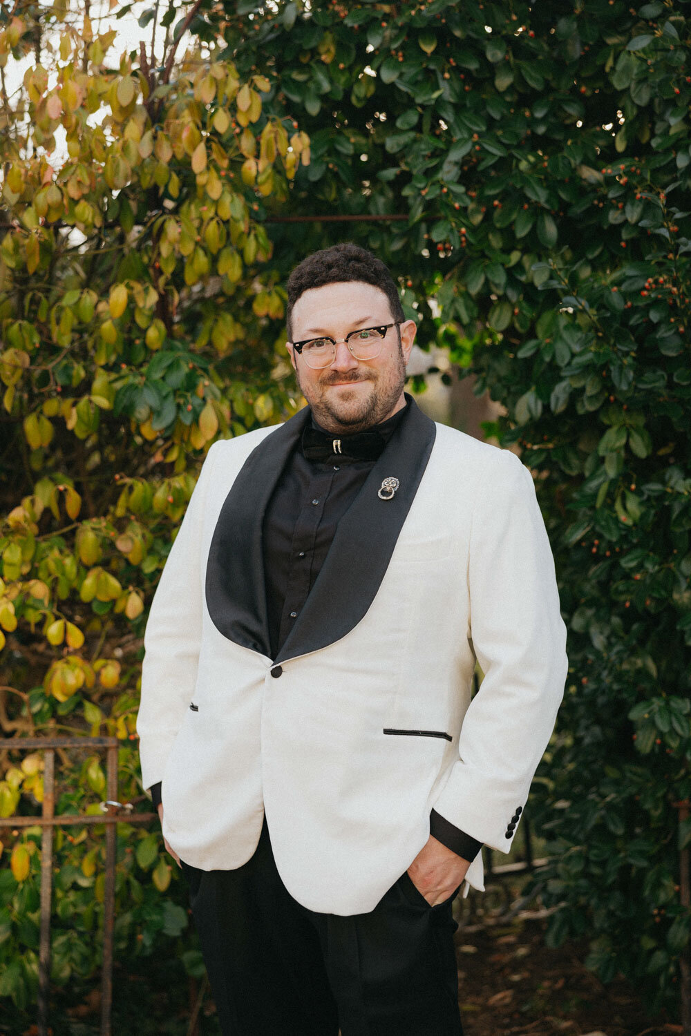 Groom in black and white suit outside