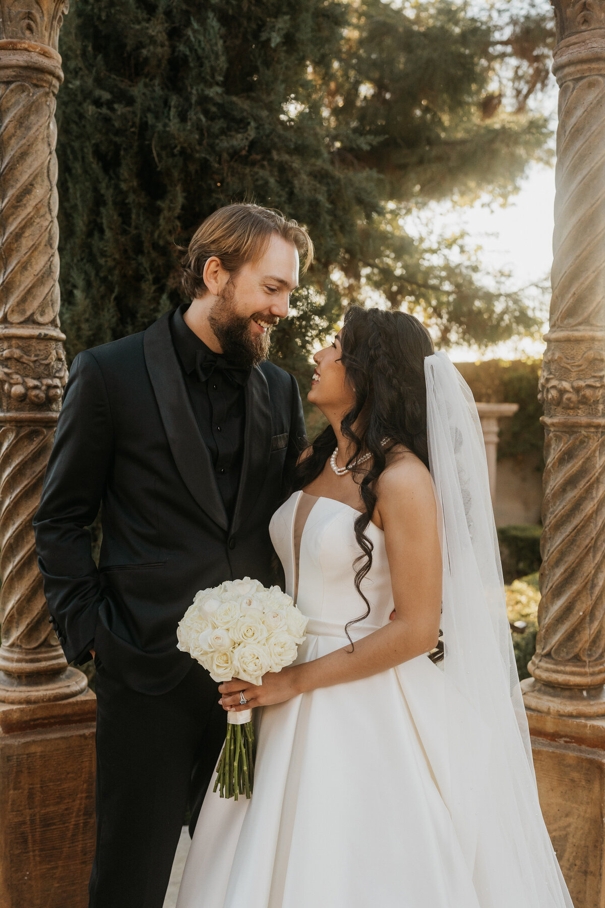 A newlywed couple standing close and looking into each other's eyes 