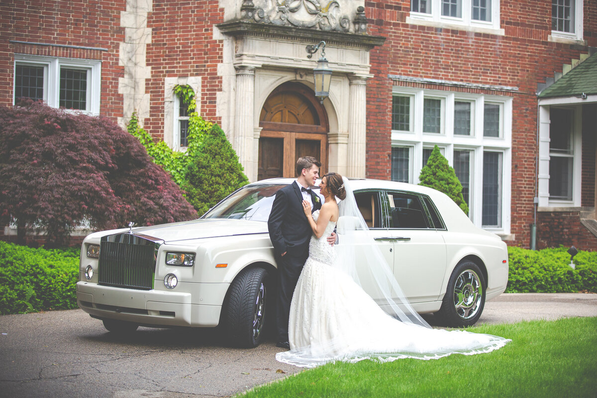 A bride and groom in front of a vintage Rolls Royce.