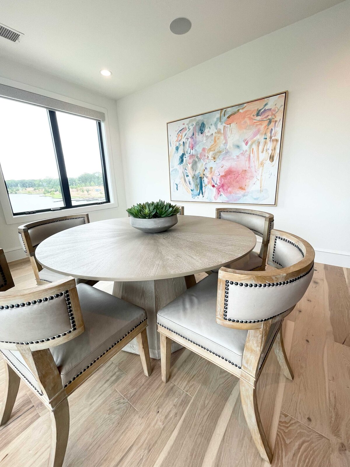 Affordable interior design service creating an amazing dining room with a peaceful atmosphere, featuring pastel colors and artwork on a white wall to enhance the serene vibe of the space.