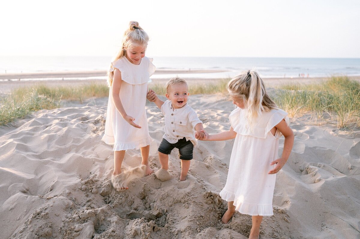 Twee zusjes en broertje rennend hand in hand over het strand