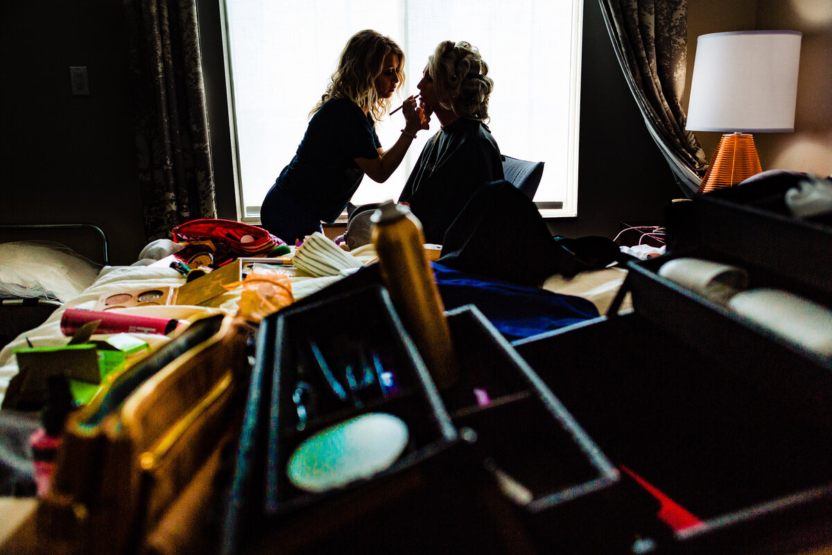 One of the top wedding photos of 2020. Taken by Adore Wedding Photography- Toledo, Ohio Wedding Photographers. This photo is of a bride getting her lipstick applied in the morning by her sister. THe wedding happened at the Hilton Garden inn in Toledo Ohio