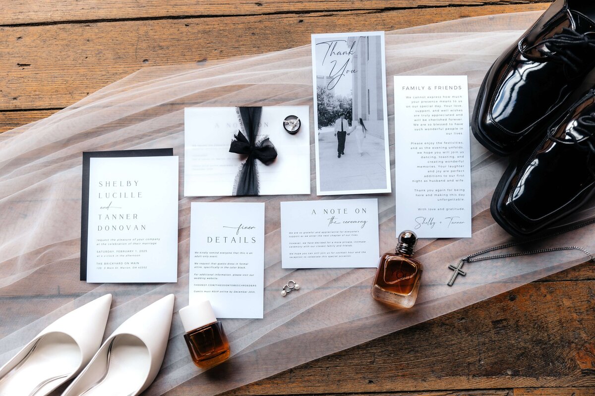 Curated wedding invitation suite and accessories on wood table, editorial-style wedding detail photography for design-focused Ohio couples