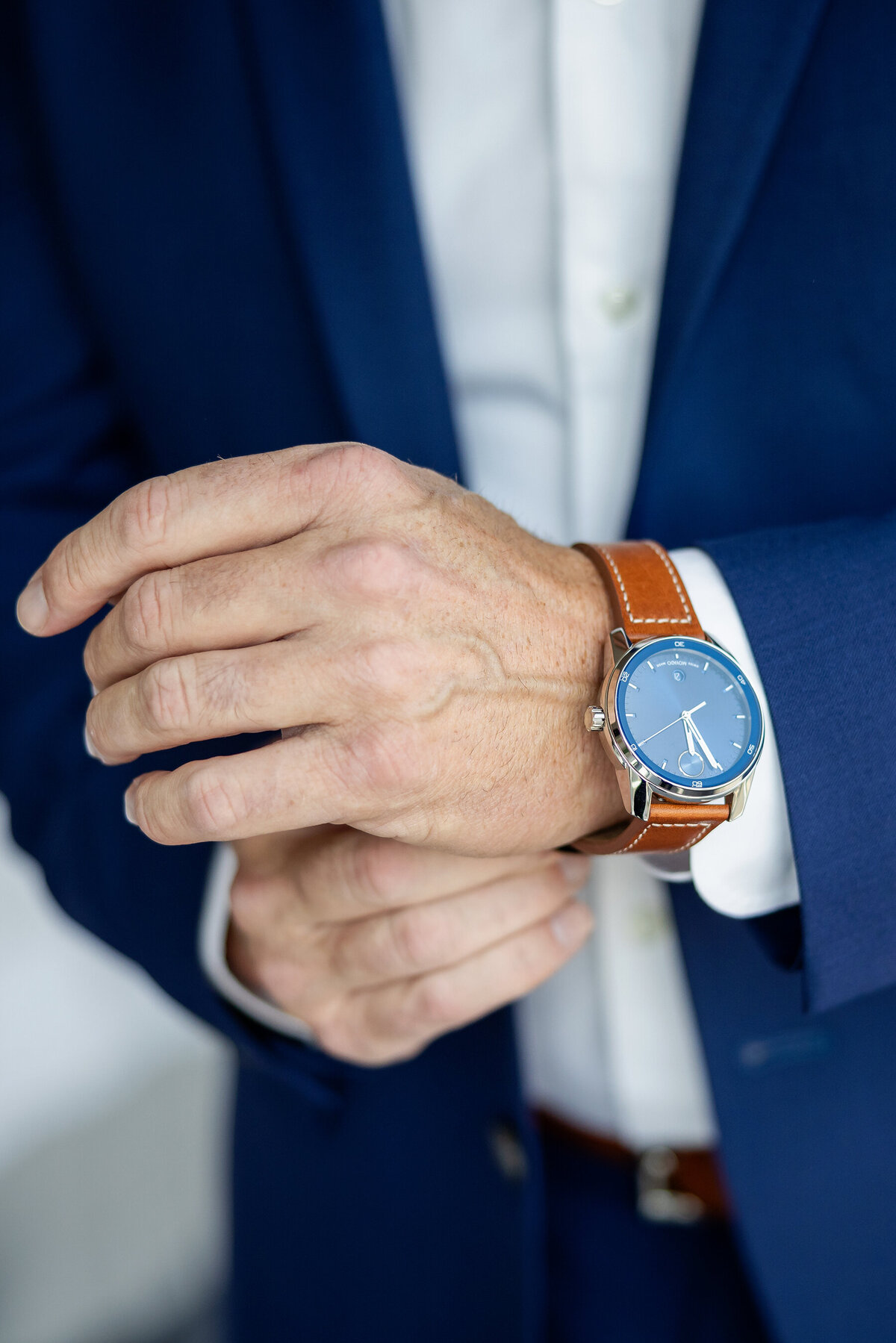 Traditional pose of groom  putting Movado Bold watch on his wrist 