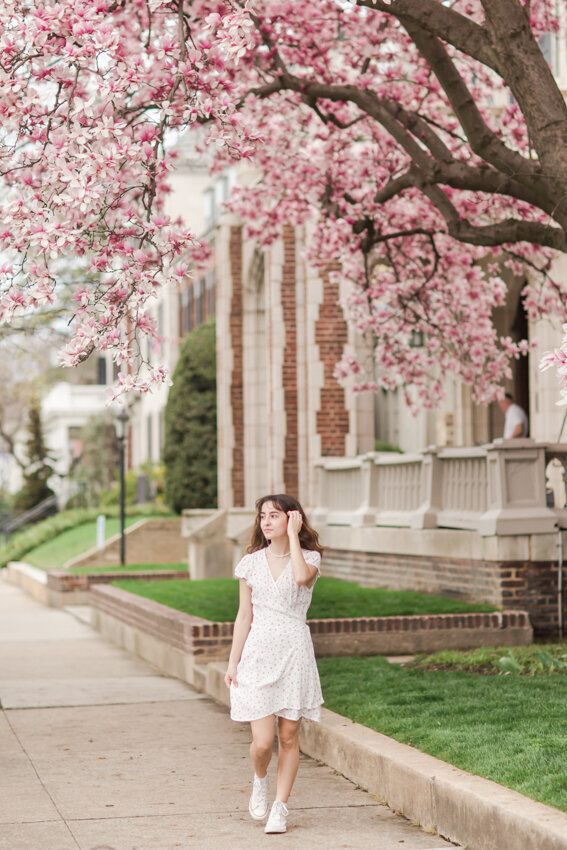 Senior girl walking under pink flowers