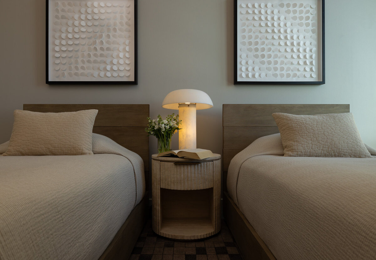 Wide shot of a secondary bedroom with twin wood bedframes, layered bedding, and a fluted travertine nightstand in a Grand Hyatt Deer Valley Airbnb