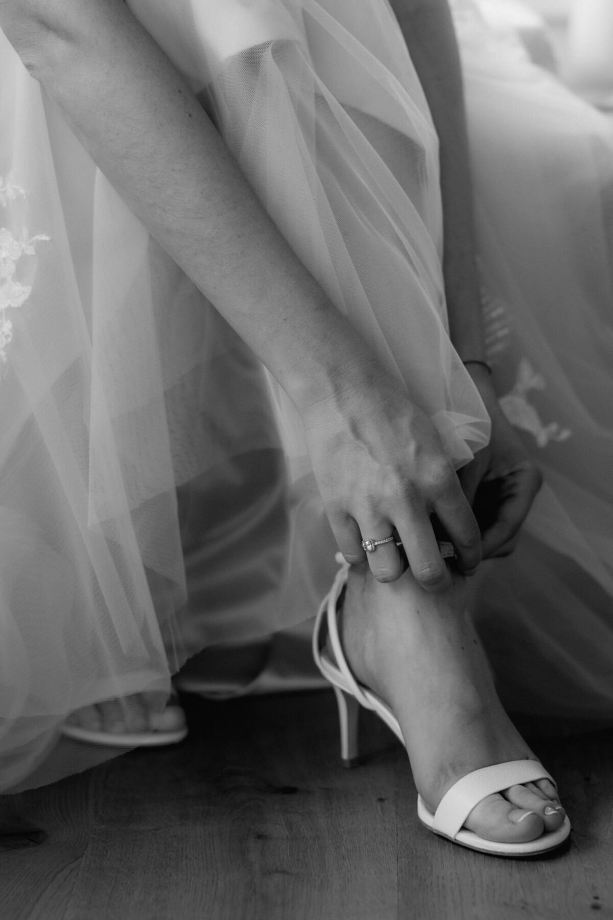 Von Nahem sieht man, wie die Braut ihr Riemchen an der Sandale schließt.