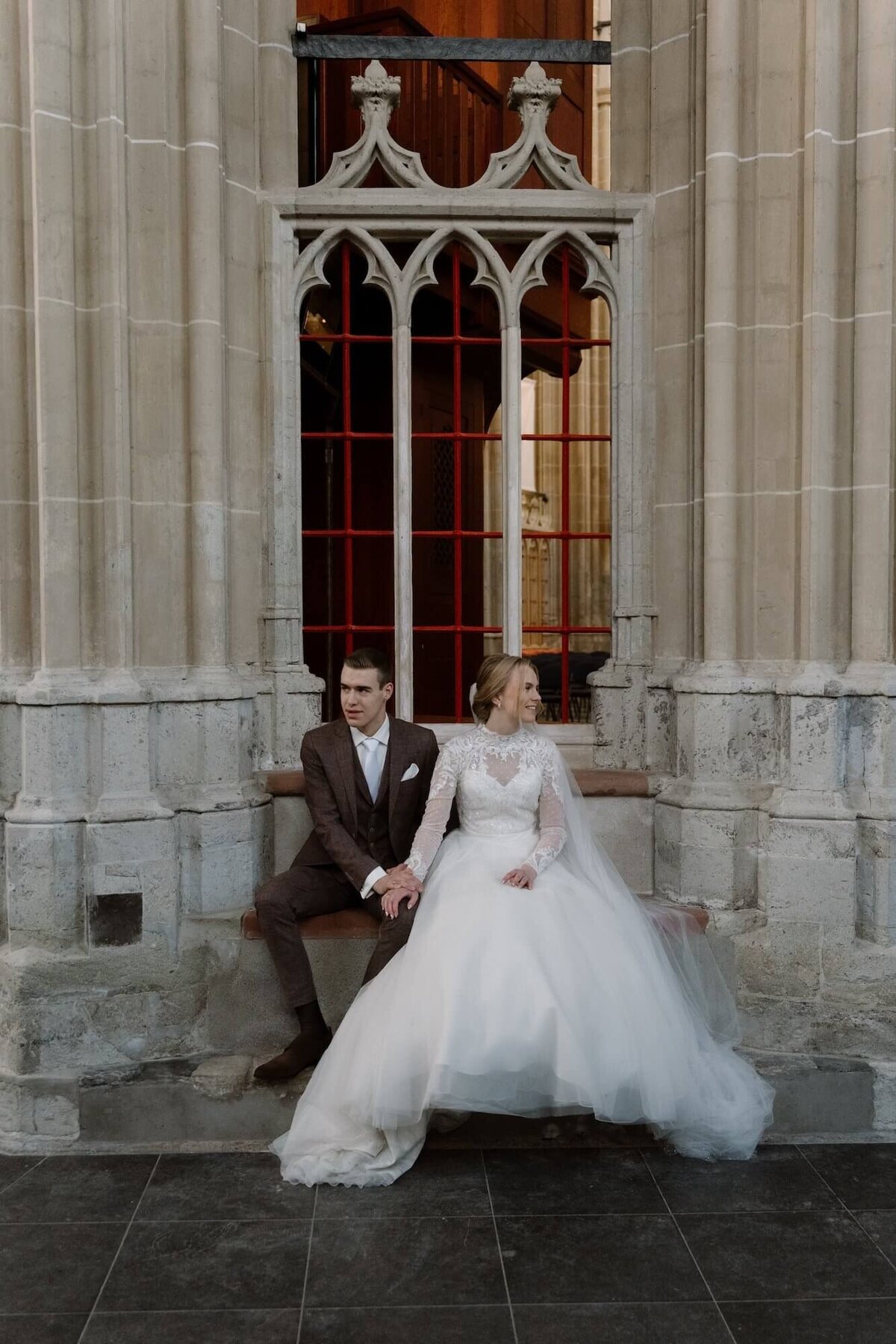 Koppel zittend op bankje voor de kerk door trouwfotograaf Julia de Groot