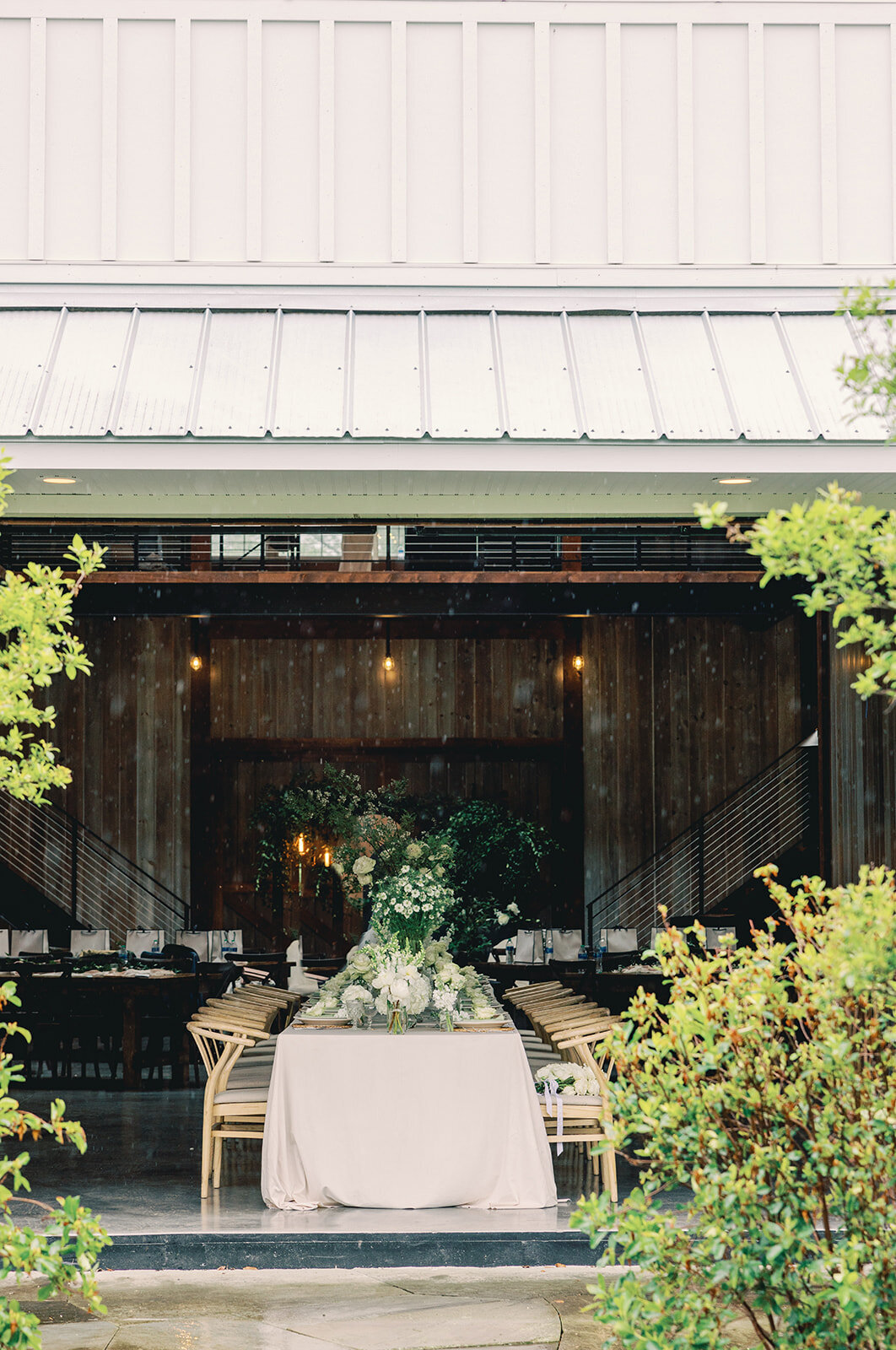 Decorated tables and chairs at the Groom in a pink jacket and bride in an elegant dress posing for a portrait at Wildflower On Watts white barn venue