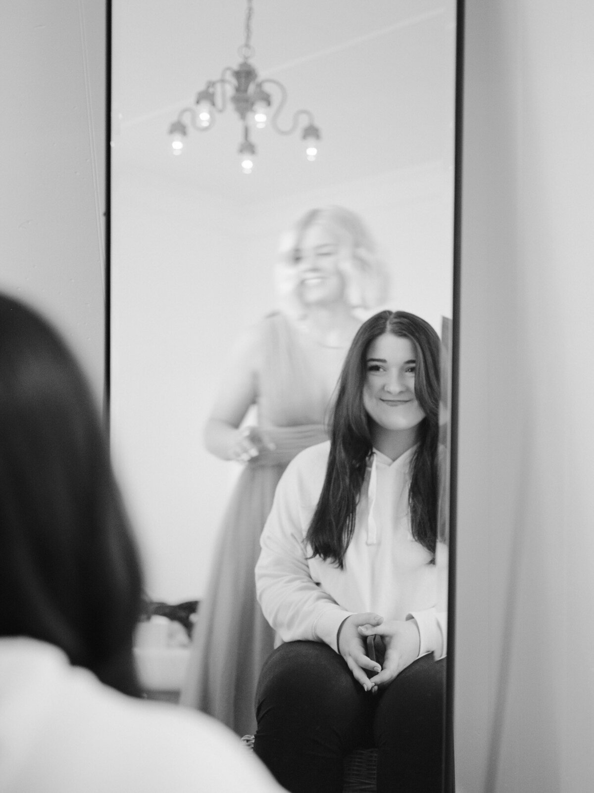 bride smiles in Mirror while getting ready at Michigan wedding venue