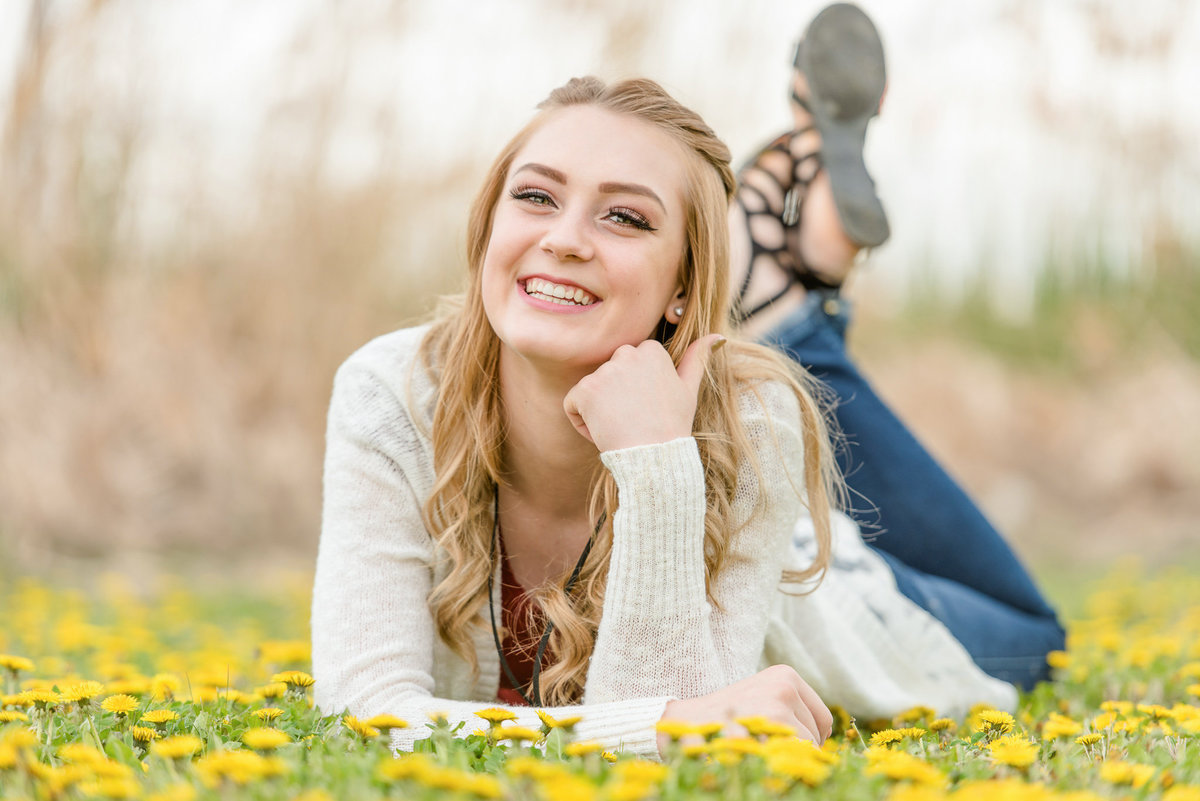 girl smiles at the camera while laying in flowers in layton utah