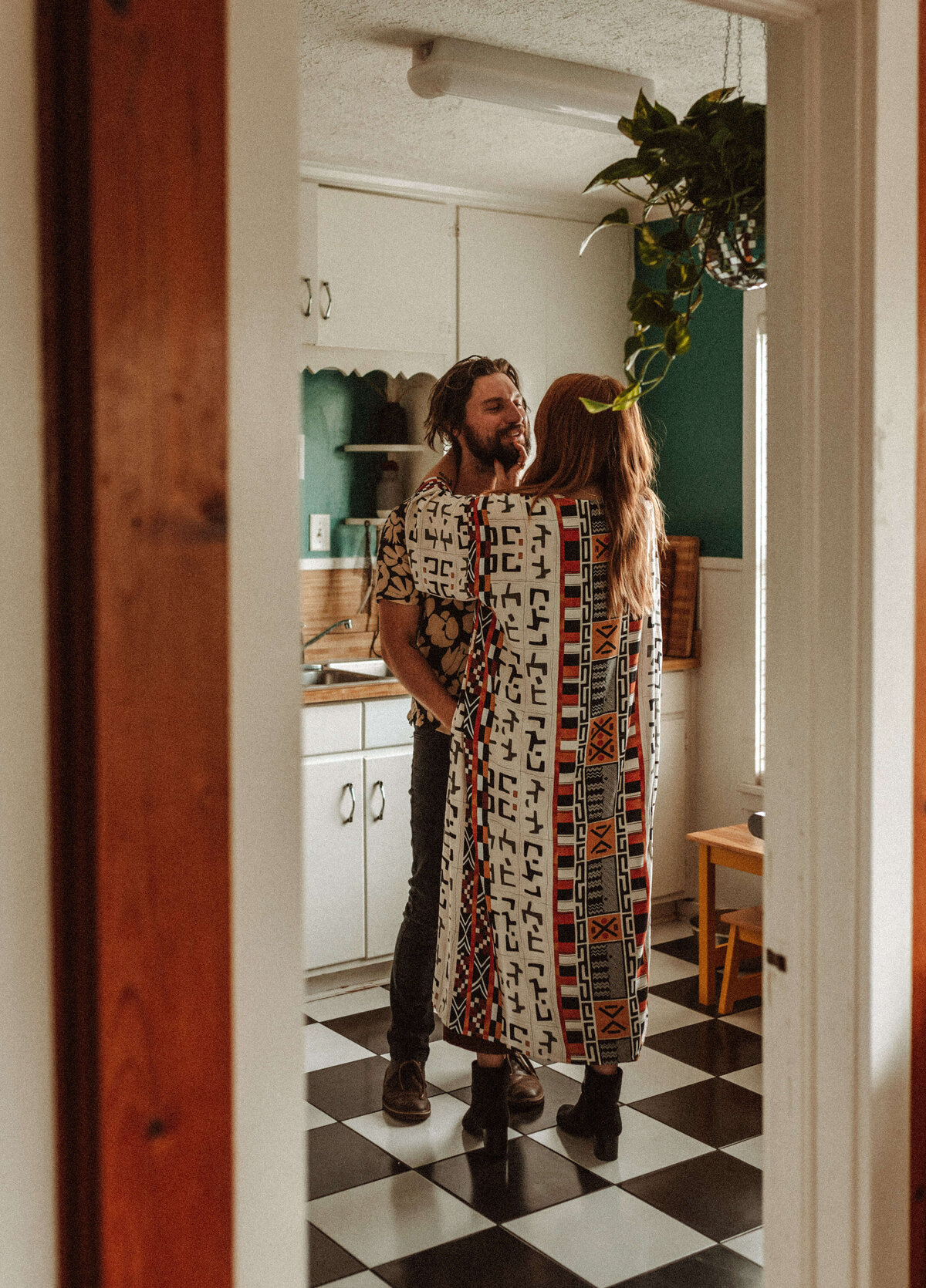 young couple chat & embrace in retro kitchen in cove home during engagement session with Be Seen Photos