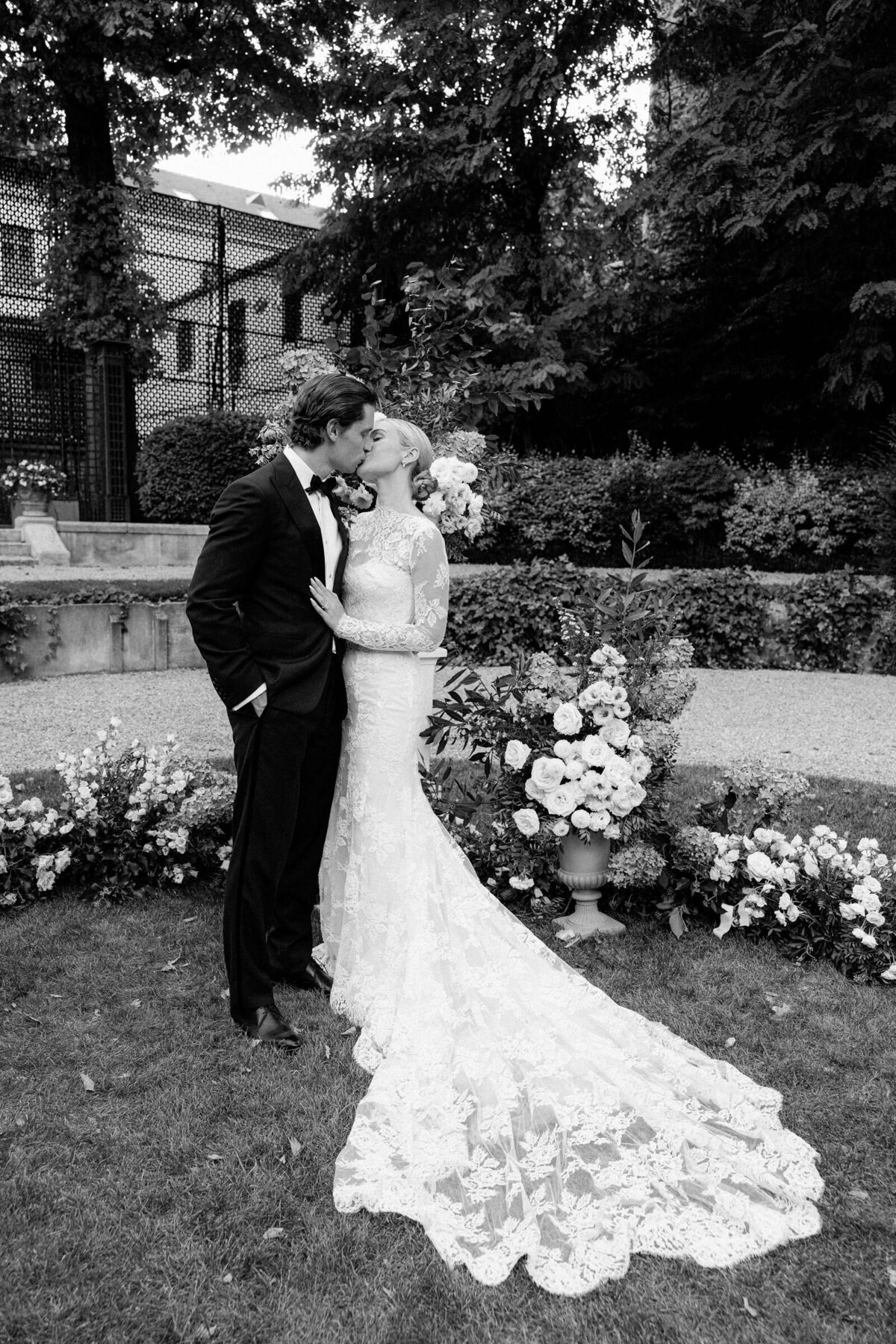 Couple sharing a kiss with lavish white florals in the background.
