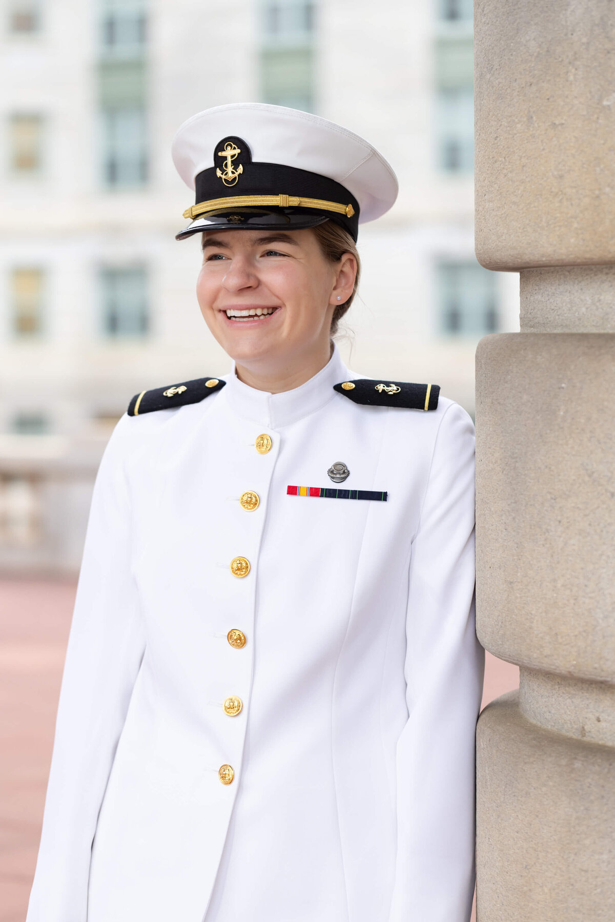 Woman Naval officer smiles in whites uniform.